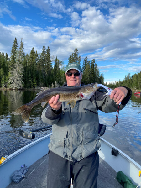 Man holding a fish freshly caught at Woman Lake Lodge Canada