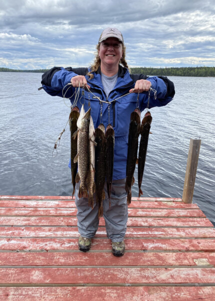 Woman holding a string of fish freshly caught at Woman Lake Lodge Canada
