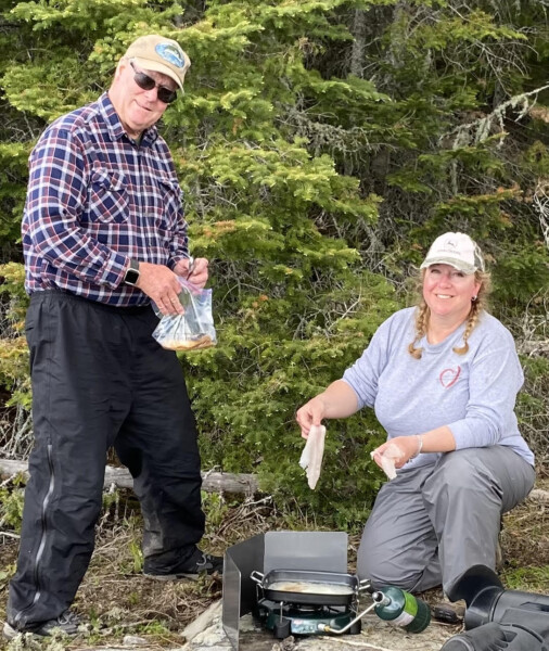 A couple grilling up a lake lunch at woman lake lodge canada