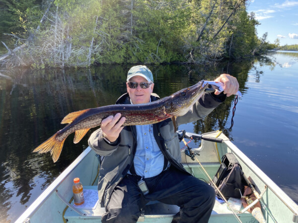 Man holding a fish freshly caught at Woman Lake Lodge Canada