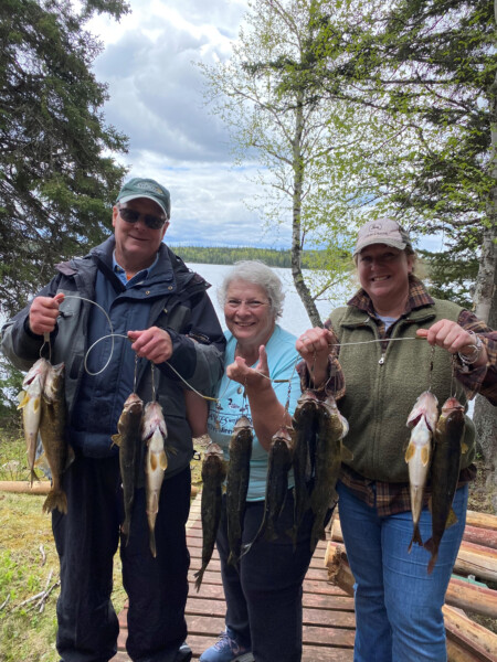 A family holding a freshly caught string of fish at Woman Lake Lodge