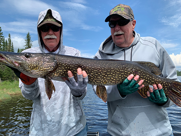 2 men hold a freshly caught fish at Woman Lake Lodge