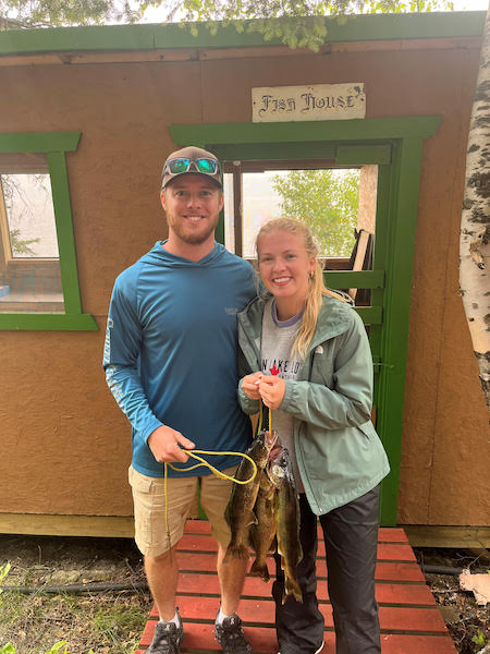 A couple holding a line of fish caught at Woman Lake Lodge