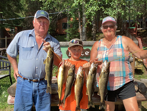 Family holding a string of freshly caught fish at Woman Lake Lodge